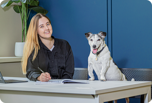 The Herano Studio founder sitting at a desk beside the studio dog